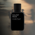 Black perfume bottle labeled 'Silent Rain' on a textured background
